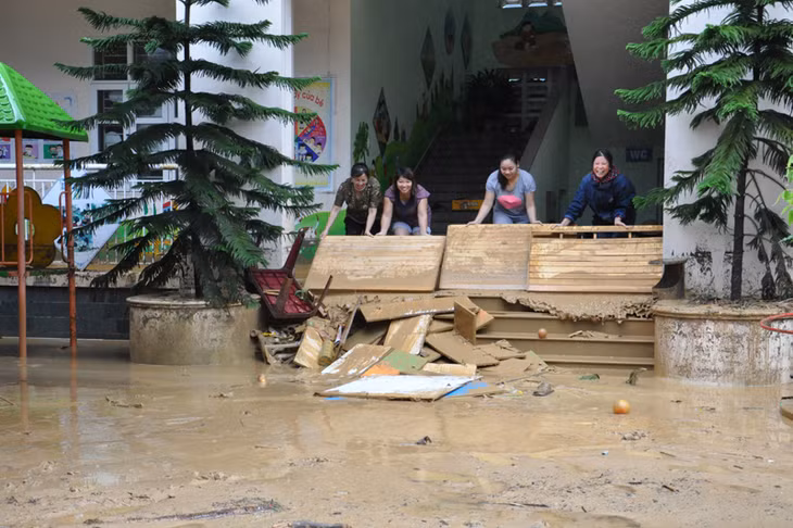 Cán bộ, giáo viên Trường Mầm non Quang Hanh phân hiệu 2 dọn dẹp bùn đất ở hàng lang các lớp học.