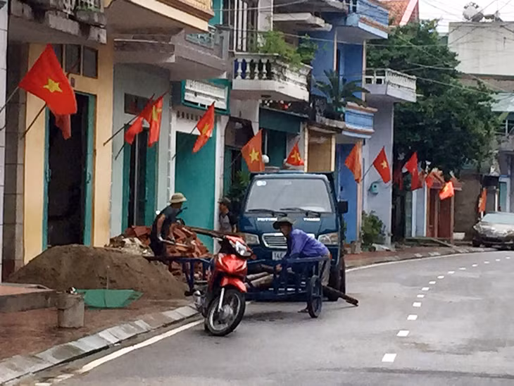 Người dân Hải Hà tranh thủ thu dọn vật liệu xây dựng lúc trời ngớt mưa.
