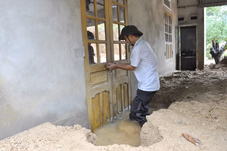 Phải khó khăn lắm ông Phạm Văn Đạt mới mở được cửa ngôi nhà của con trai ông ở tổ 6, khu 7, phường Quang Hanh do nước và cát ngập đến lưng nhà
