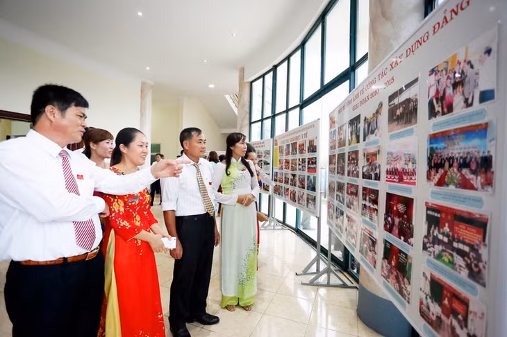Các đại biểu xem triển lãm thành tựu của Đảng bộ huyện nhiệm kỳ qua.