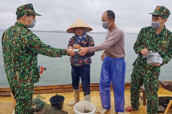 CBCS Đồn Biên phòng Trà Cổ tuyên truyền về phòng, chống thiên tai và phát khẩu trang cho bà con ngư dân. Ảnh: Hữu Việt.