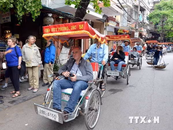 Du khách nước ngoài thăm phố cổ Hà Nội bằng xe xích lô. (Ảnh: Thanh Hà/TTXVN)