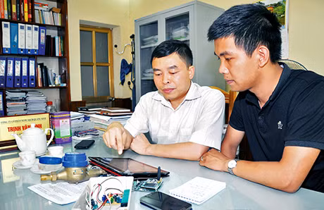 Thạc sĩ Trịnh Văn Bình (bên trái) giới thiệu nguyên lý hoạt động của hệ thống giám sát lưu lượng và áp lực nước từ xa qua mạng internet GSM/GPRS/3G. Ảnh: Lương Giang
