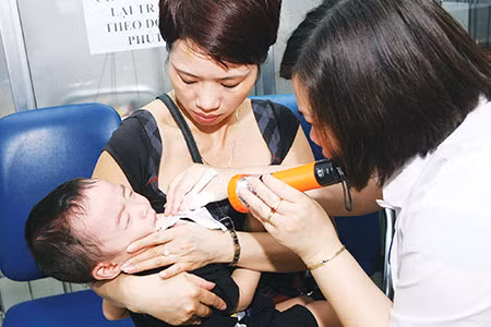Khi trẻ có dấu hiệu viêm họng cần đưa trẻ đi khám để được điều trị đúng. Ảnh: Trần Minh