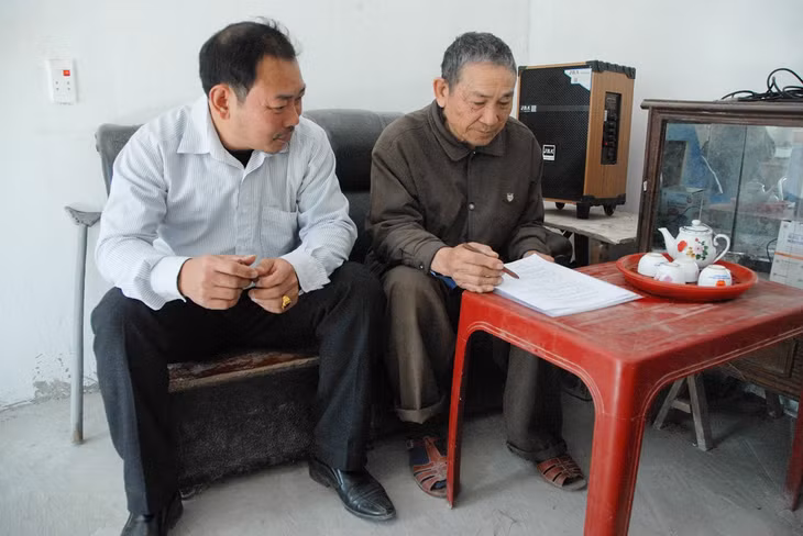 Cán bộ xã Quảng An, huyện Đầm Hà (bên trái) nắm tình hình hộ ông Nguyễn Văn Huân sau khi được công nhận thoát nghèo