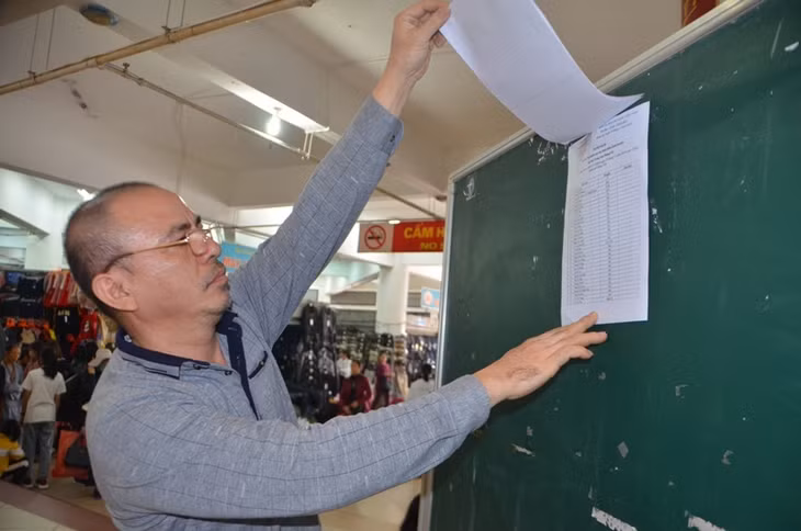 Ông Phạm Quốc Minh, chủ hộ kinh doanh tại tầng 1 Chợ Trung tâm Móng Cái xem phần trả lời công khai của UBND TP Móng Cái về trả lời kiến nghị của một số hộ kinh doanh.