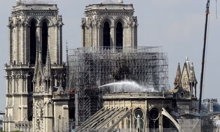 Lính cứu hỏa phun nước dập tắt ngọn lửa trong vụ cháy Nhà thờ Đức bà Paris hồi tháng 4. Ảnh: CNN.