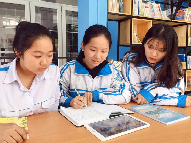Lô Vũ Bình Minh (ngồi giữa) cùng các bạn trao đổi về ứng dụng mang tên “Lịch sử và du lịch Việt Nam” trên hệ điều hành Android do mình xây dựng.
