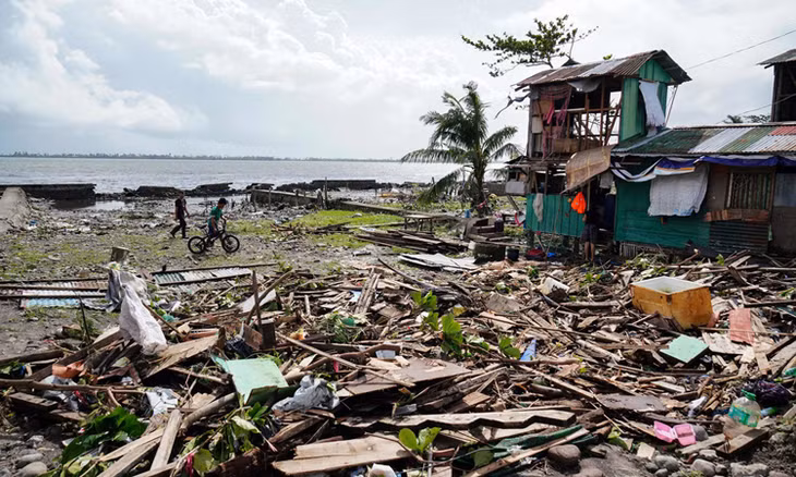 Người dân đi qua một ngôi nhà bị tàn phá ở tỉnh Leyte, miền trung Philippines hôm 25/12. Ảnh: AFP.