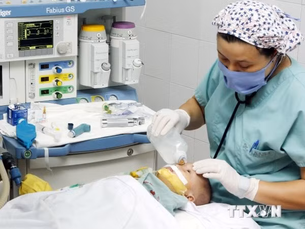Nhân viên y tế chăm sóc cho trẻ sau khi tiến hành một ca phẫu thuật khe hở môi, vòm miệng. (Ảnh: TTXVN)