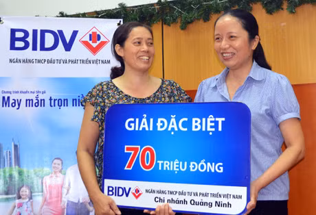 Chị Vũ Thị Xuyên (áo hoa) nhận sổ tiết kiệm trị giá 70 triệu đồng.