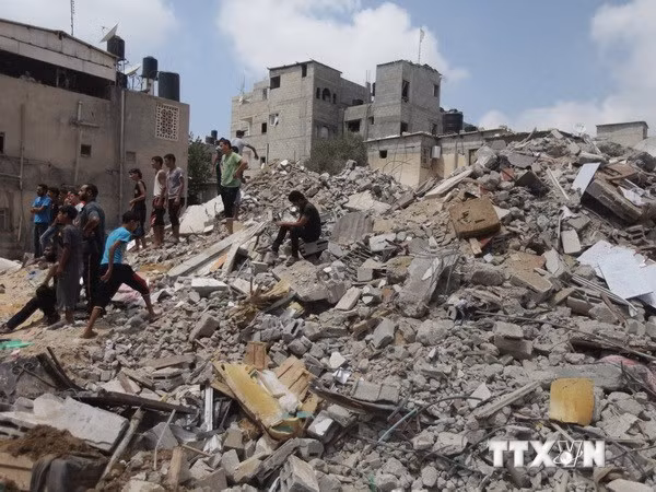 Người dân Palestine nỗ lực tìm kiếm người sống sót dưới đống đổ nát sau vụ không kích của Israel. (Ảnh: THX/TTXVN)