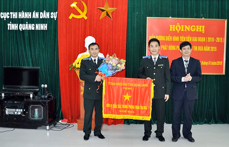 Đồng chí Lê Quang Tùng, Phó Chủ tịch UBND tỉnh tặng cờ đơn vị dẫn đầu phong trào thi đua công tác thi hành án năm 2014 của UBND tỉnh cho Chi cục Thi hành dân sự TP Cẩm Phả. Ảnh: Nguyễn Huế