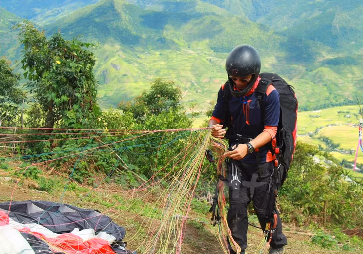 Một phi công kiểm tra dây dù trước khi bay. (Ảnh: Xuân Mai/Vietnam+)