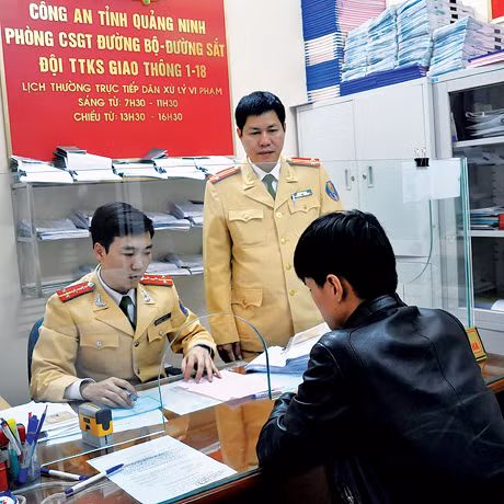 Trung tá Vũ Đình Sơn (đứng) tuyên truyền về pháp luật ATGT và giải quyết thủ tục cho người tham gia giao thông.