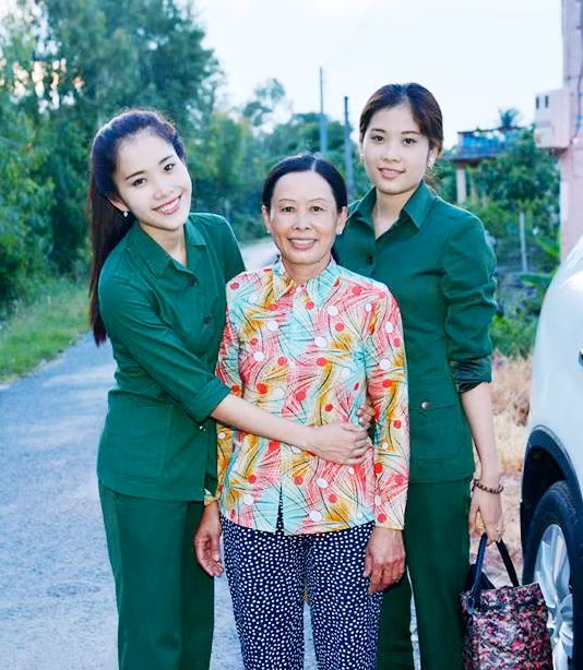 Nam Em (trái) chụp ảnh cùng mẹ (giữa) và chị gái sinh đôi (phải) trong ngày giỗ cha (5/8) mới đây. Ảnh: NVCC.