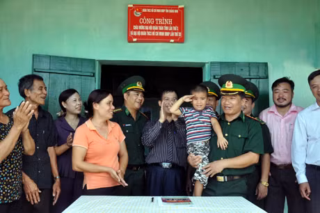 Cán bộ Đồn BP Đảo Trần đến thăm và nhận đỡ đầu cháu bé của gia đình đầu tiên đến định cư trên đảo.