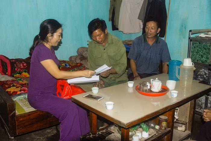 Cán bộ Mặt trận thôn Cửa Khẩu, xã Hoành Mô, huyện Bình Liêu (bên trái) hướng dẫn người dân ký cam kết giữ vệ sinh môi trường nông thôn