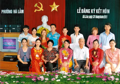 Chị Minh Nguyệt (thứ hai hàng ngồi, từ trái sang) thay mặt UBND phường chụp ảnh lưu niệm trong một buổi lễ đăng ký kết hôn tại trụ sở phường.