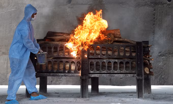 Một nhân viên tẩm chất lỏng bắt cháy lên giàn hỏa táng người chết vì Covid-19 tại ngoại ô Mumbai hôm 15/4. Ảnh: Reuters.