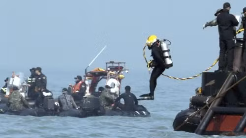 Một thợ lặn nhảy xuống nước để tìm kiếm những người bị kẹt trên phà Sewol (Ảnh AP)