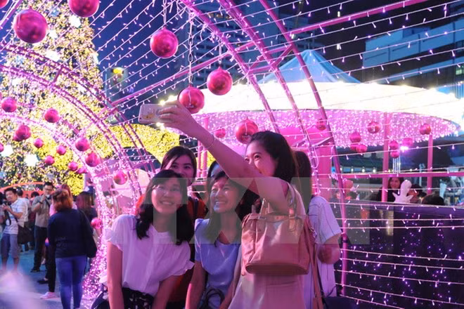 Du khách chụp ảnh tại một trung tâm mua sắm ở thủ đô Bangkok. (Nguồn: THX/TTXVN)