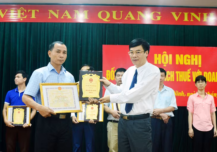 Đồng chí Trần Văn Ninh, Cục trưởng Cục Thuế Quảng Ninh trao bằng khen của Tổng cục Thuế Việt Nam cho các đơn vị, doanh nghiệp hoàn thành xuất sắc nghĩa vụ nộp thuế, thu phí và lệ phí năm 2015.