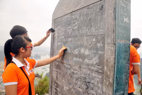 Đánh sạch chữ viết bậy trên bia đá.