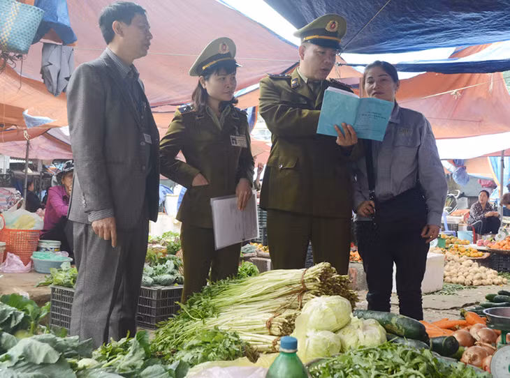 Lực lượng chức năng TP Uông Bí hướng dẫn hộ tiểu thương chợ Trung tâm TP ghi nhật ký xuất, nhập hàng hóa. Ảnh Cao Quỳnh