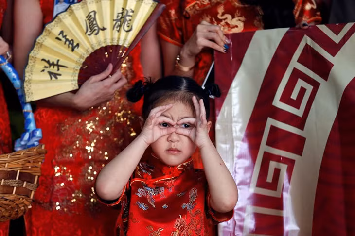 Một em bé Thái Lan trong trang phục truyền thống Trung Quốc chào đón du khách Trung Quốc nhân dịp năm mới tại sân bay Don Mueang, Bangkok.