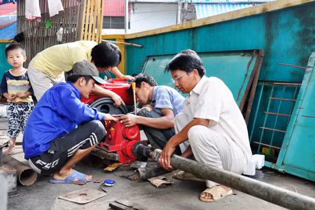 Anh Đinh Văn Giang (ngoài cùng, bên phải) hoàn thiện mô hình máy hút bùn, chuẩn bị tham gia hội thi Sáng tạo kỹ thuật nông nghiệp nông thôn lần I.