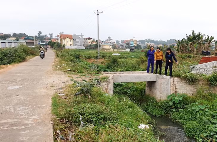 Chị Hoàng Thị Thúy (áo tím, hội viên tôn giáo điển hình) với cây cầu mà gia đình tự bỏ tiền xây dựng
