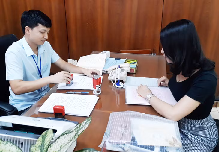 Cán bộ Trung tâm hành chính công thành phố làm thủ tục cấp giấy chứng nhận quyền sử dụng đất cho người dân.