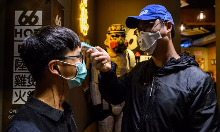 Chủ một nhà hàng ở Hong Kong đo thân nhiệt cho nhân viên hôm 13/2. Ảnh: AFP.