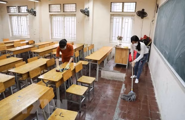 Giáo viên Trường THPT Trương Định, Hà Nội tiến hành vệ sinh, khử khuẩn lớp học lần 2 trong ngày 8/2. (Ảnh: Thanh Tùng/TTXVN)