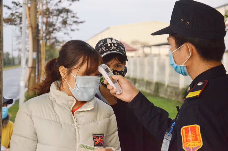 Công nhân làm việc tại Công ty TNHH Khoa học kỹ thuật Texhong Ngân Long được đo thân nhiệt trước khi vào làm việc. (Ảnh: Nguyễn Thanh)