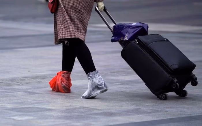 Giày được bao bọc thêm bằng túi nylon để ngăn chặn lây nhiễm Covid-19. Ảnh: Reuters.