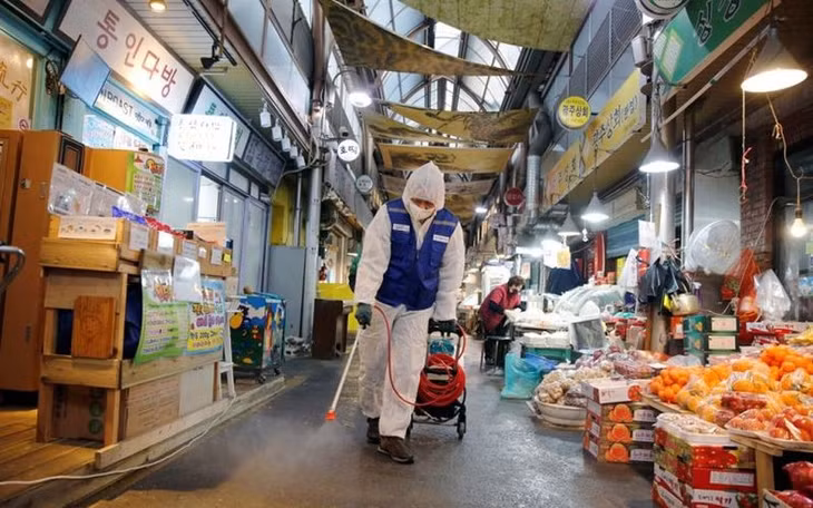 Nhân viên y tế phun thuốc khử trùng tại một khu chợ ở Hàn Quốc. Ảnh: Reuters