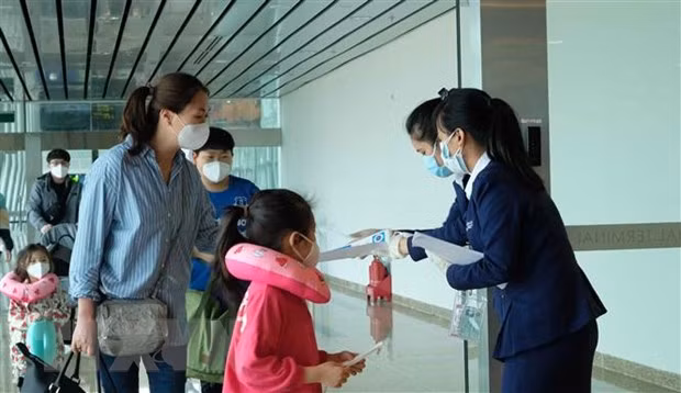 Nhân viên Sân bay quốc tế Cam Ranh phát tờ rơi hướng dẫn phòng dich COVID-19 cho hành khách tại khu vực nhập cảnh. (Ảnh: Nguyễn Dũng/TTXVN)
