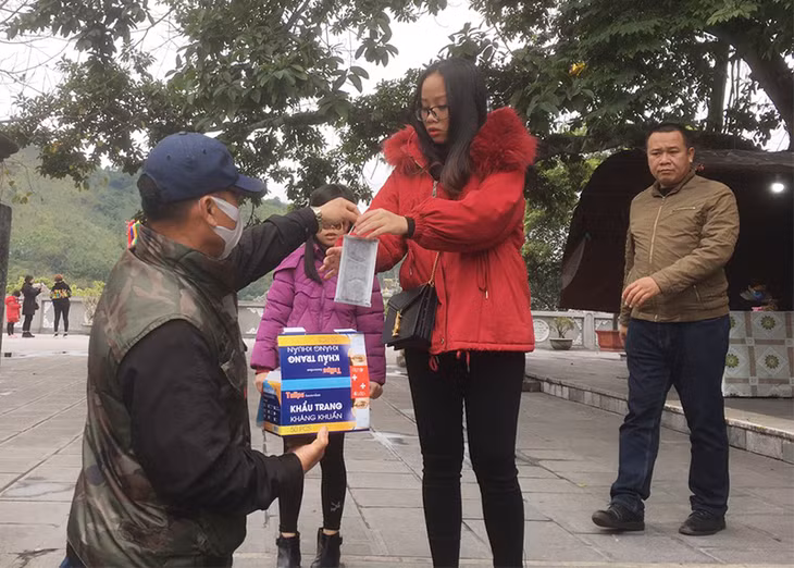 Nhân viên Ban Quản lý Đền Cửa Ông phát khẩu trang miễn phí.