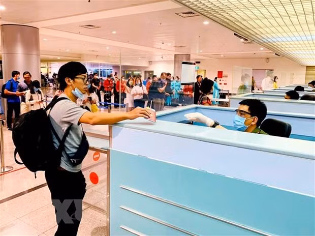 Cán bộ công an cửa khẩu Tân Sơn Nhất chủ động trang bị đầy đủ khẩu trang, găng tay trong khi làm nhiệm vụ. (Ảnh: Thành Chung/TTXVN)