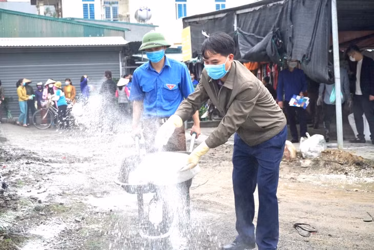 Người dân tham gia rắc vôi bột khử trung tại khu vực chợ dân sinh trên địa bàn xã Thống Nhất.