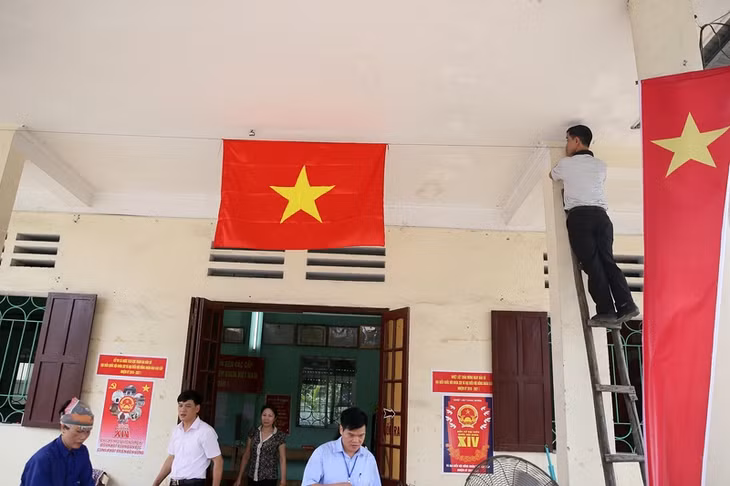 Cán bộ Khu phố 2, phường Quang Hanh treo cờ tổ quốc chuẩn bị cho bầu cử tại Nhà văn hóa khu.