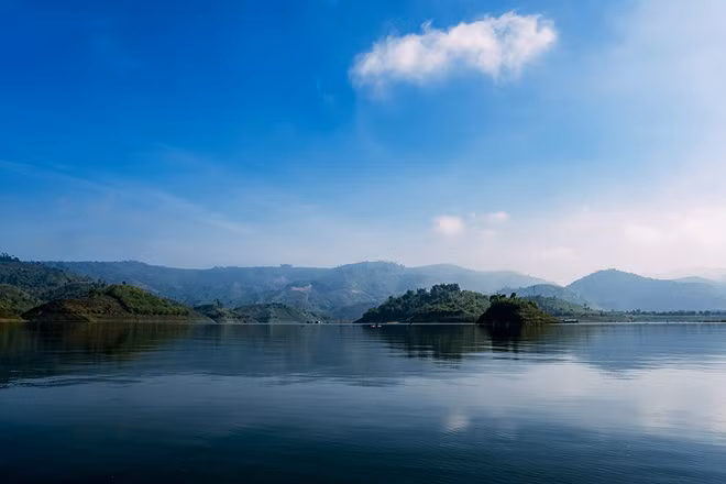 Giữa các dãy núi phủ đầy cây cối, một mặt nước xanh trong hiện lên với những cồn, đồi nhỏ. Vào buổi sớm tinh sương, bạn sẽ ngỡ đã đi lạc tới một vùng đất xa xôi nào đó chứ không còn giữa đại ngàn Tây Nguyên hùng vĩ.