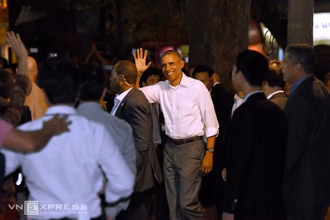  Hơn 20h ngày 23/5, Tổng thống Mỹ Obama xuất hiện tại phố Lê Văn Hưu (Hai Bà Trưng) để thưởng thức món bún chả Hà Nội. Trước đó nhiều giờ, quán ăn trên phố này có nhiều nhân viên an ninh nước ngoài lẫn Việt Nam kiểm tra nghiêm ngặt. Khách bước vào quán phải qua vài vòng an ninh. Khác với vẻ ngoài trang trọng khi tham dự các hoạt động chính thức, Tổng thống Mỹ mặc sơ mi trắng, tươi cười với người dân khi bước vào quán. Ảnh: Giang Huy.