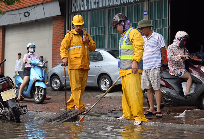  Công nhân thoát nước ứng trực tại hiện trường để vớt rác tại miệng thu hàm ếch, khơi thông dòng chảy. Trạm bơm Yên Sở, trạm bơm Đồng Bông I, Đồng Bông II và các trạm bơm cục bộ khác liên tục vận hành để hạ mực nước trên hệ thống. Ảnh: Ngọc Thành.