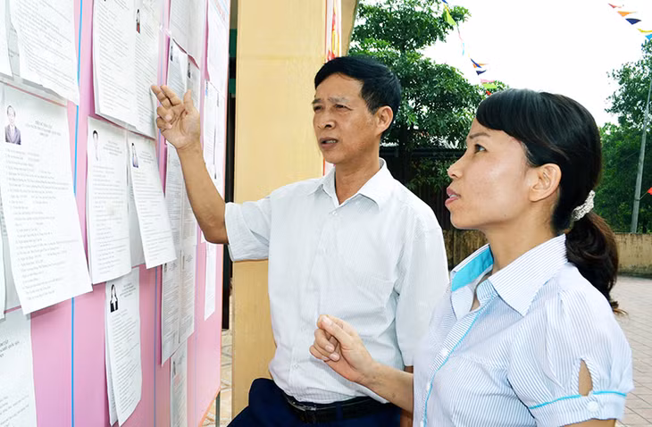 Cán bộ HND huyện Hoành Bồ và thị trấn Trới kiểm tra việc niêm yết danh sách người tham gia ứng cử tại Nhà văn hoá khu 8, thị trấn Trới. (Ảnh chụp ngày 19-5-2016)