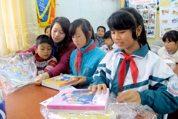 Niềm vui của các em học sinh khi được nhận đồ dùng học tập và quần áo của anh chị ĐVTN.
