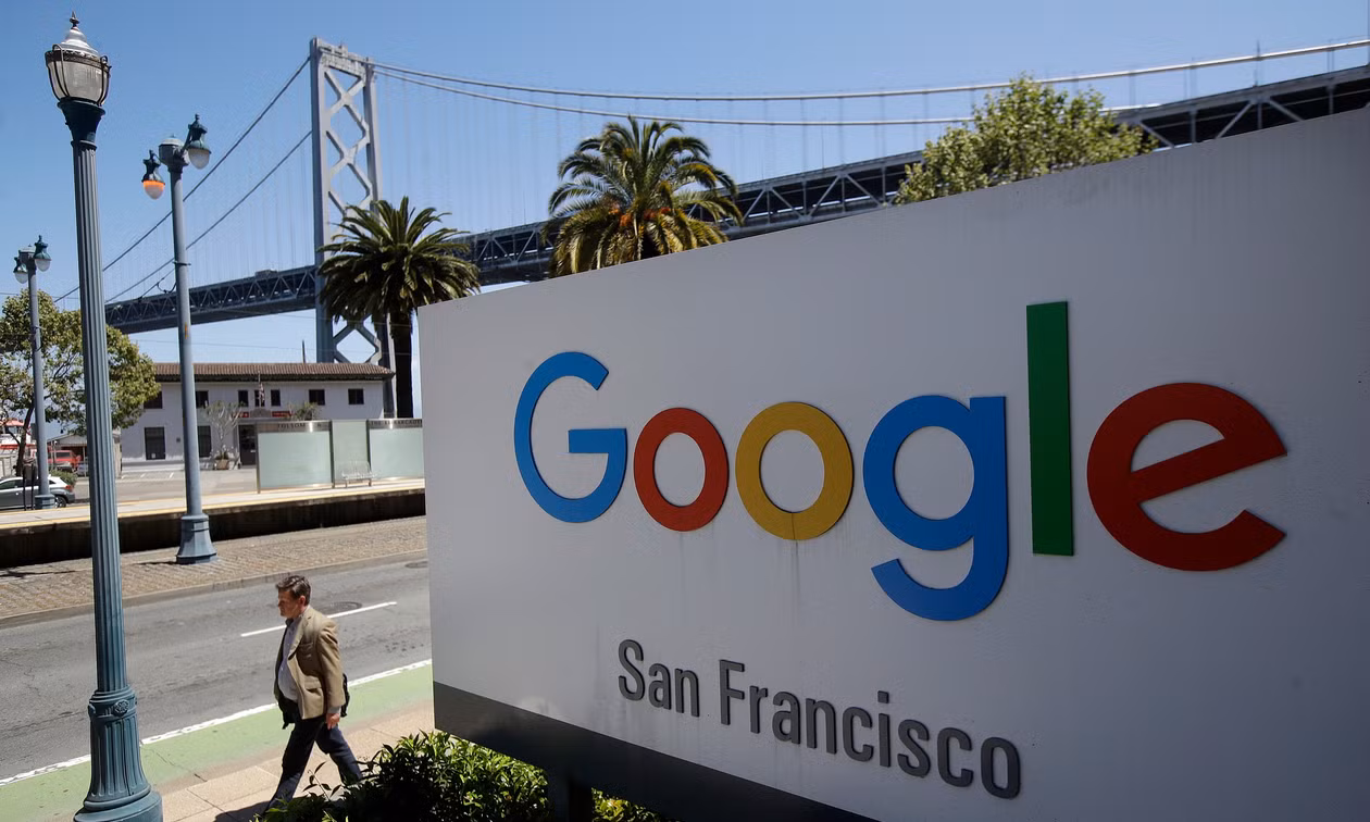 Một người đàn ông đi ngang qua biển hiệu Google tại San Francisco, Mỹ, phía sau là một nhịp cầu Bay Bridge, ngày 1/5/2019. Ảnh: AP