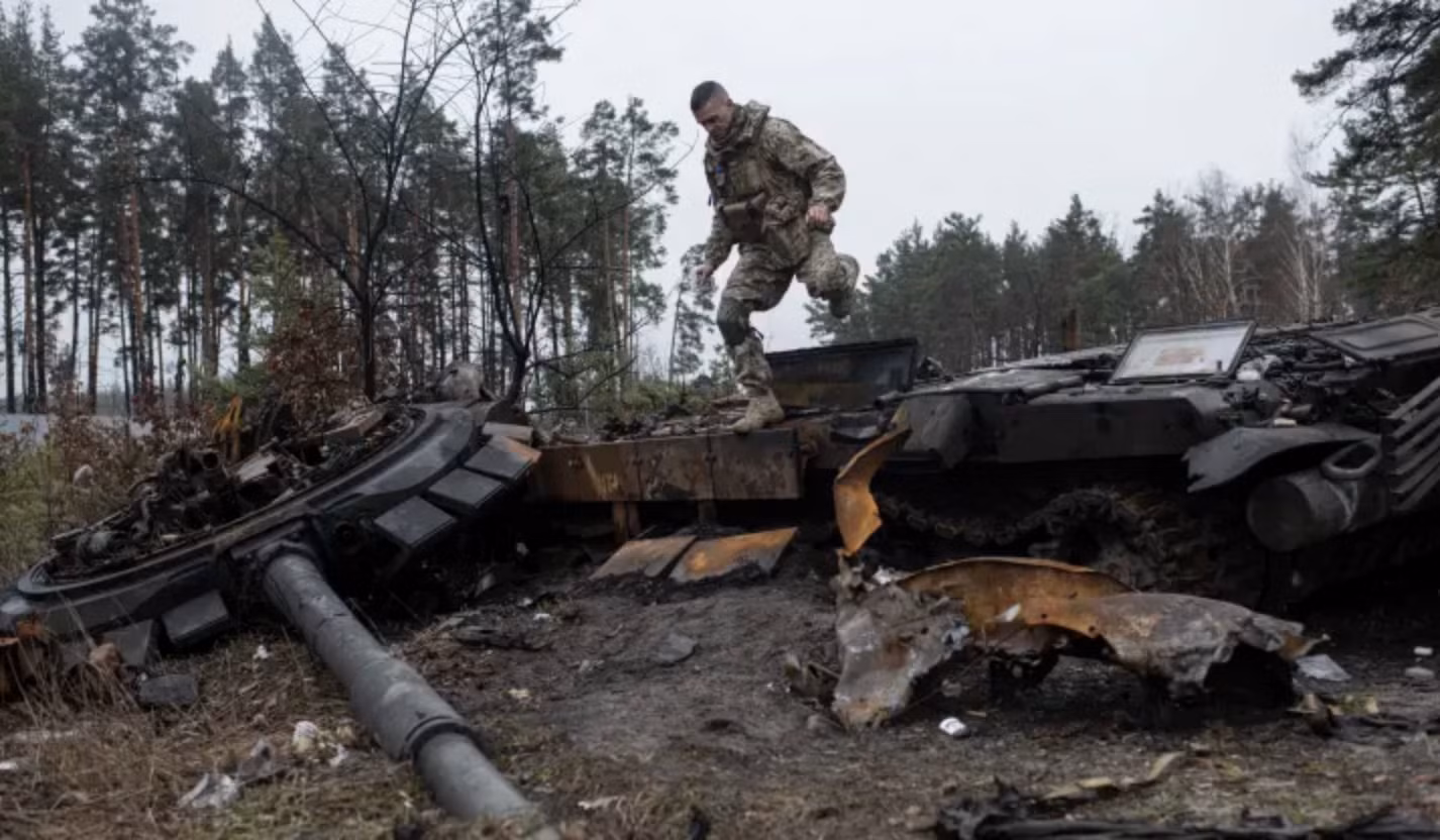 Binh sĩ Ukraine vượt qua một xác xe tăng ở Dmytrivka, ngoại ô Kiev ngày 2/4/2022. Ảnh: Getty Images